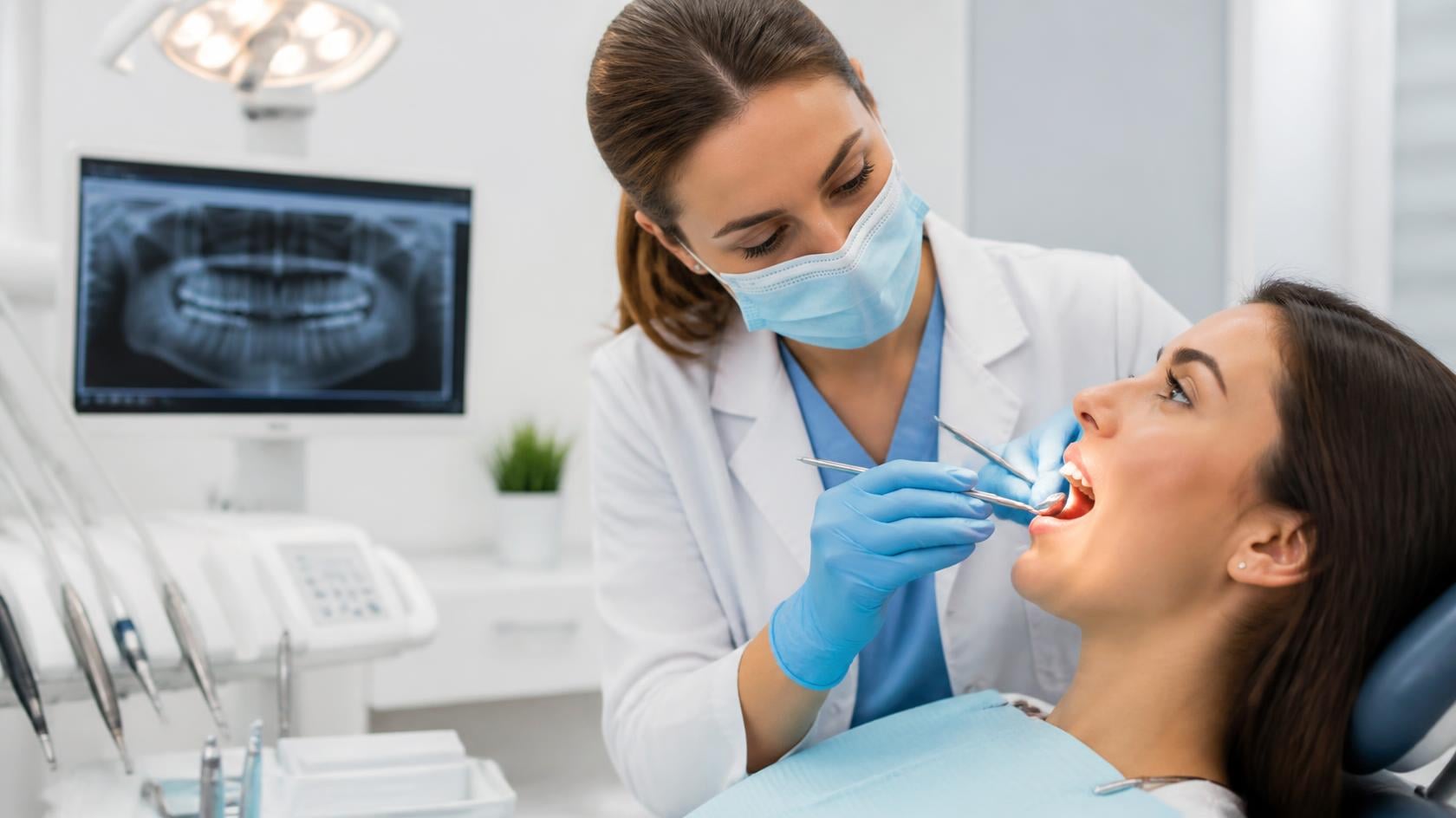 A professional dental clinic scene with a dentist examining a patient's gums.